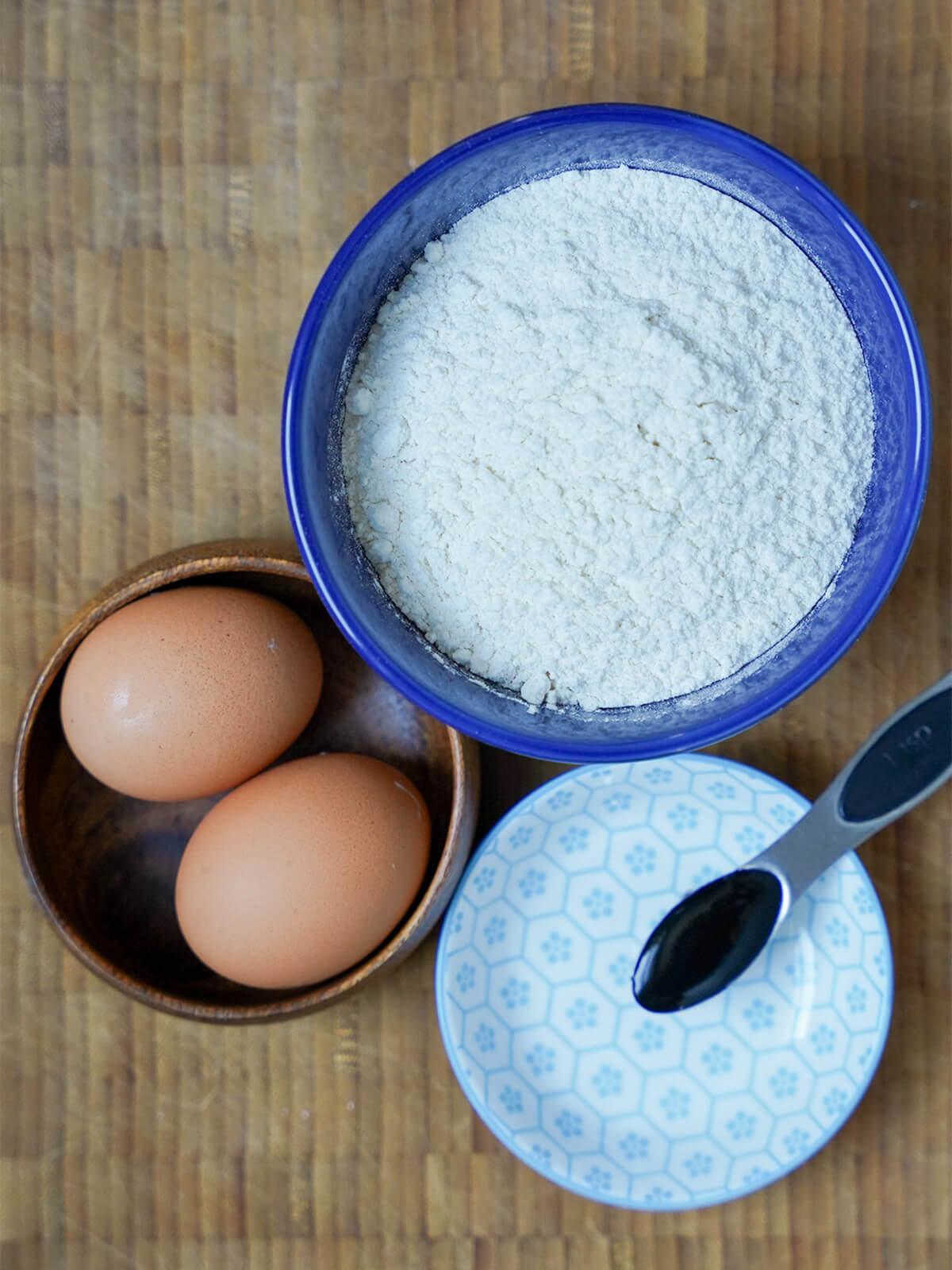 bowls with eggs, flour and a spoon of cuttlefish ink.