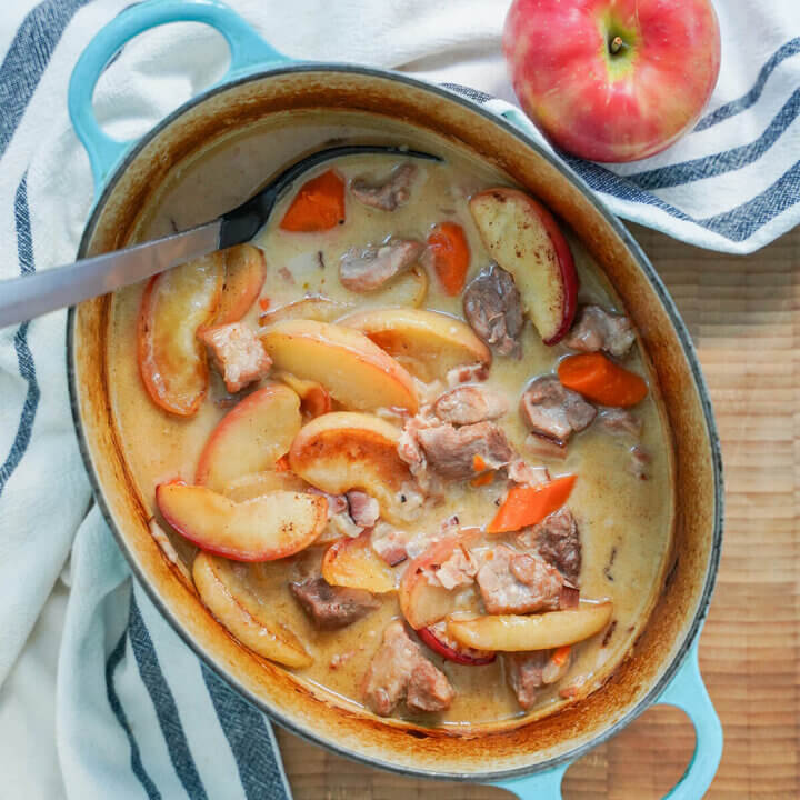 pot of pork and cider casserole with spoon in top.