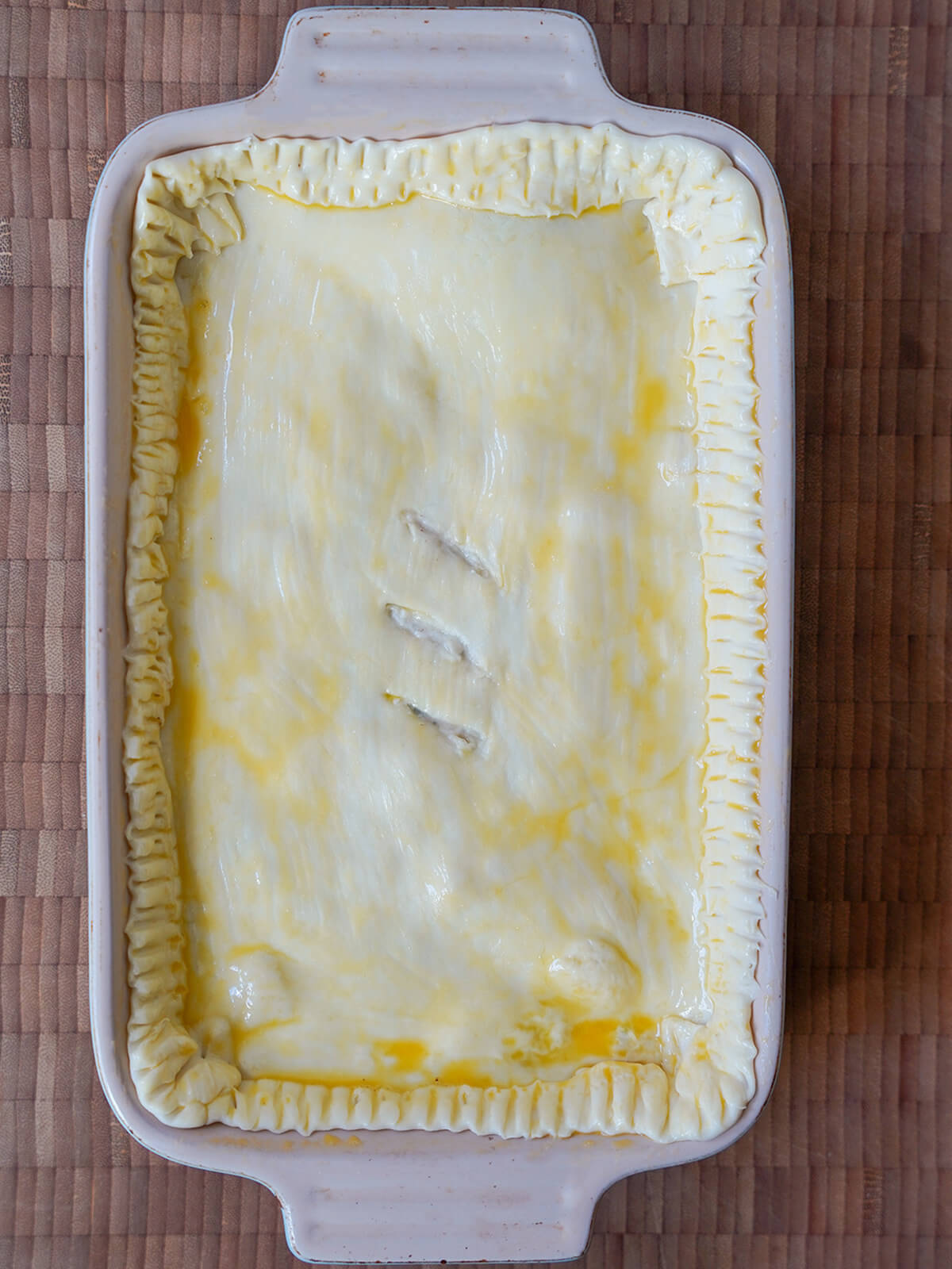 dish with pastry over pie brushed with egg before baking.