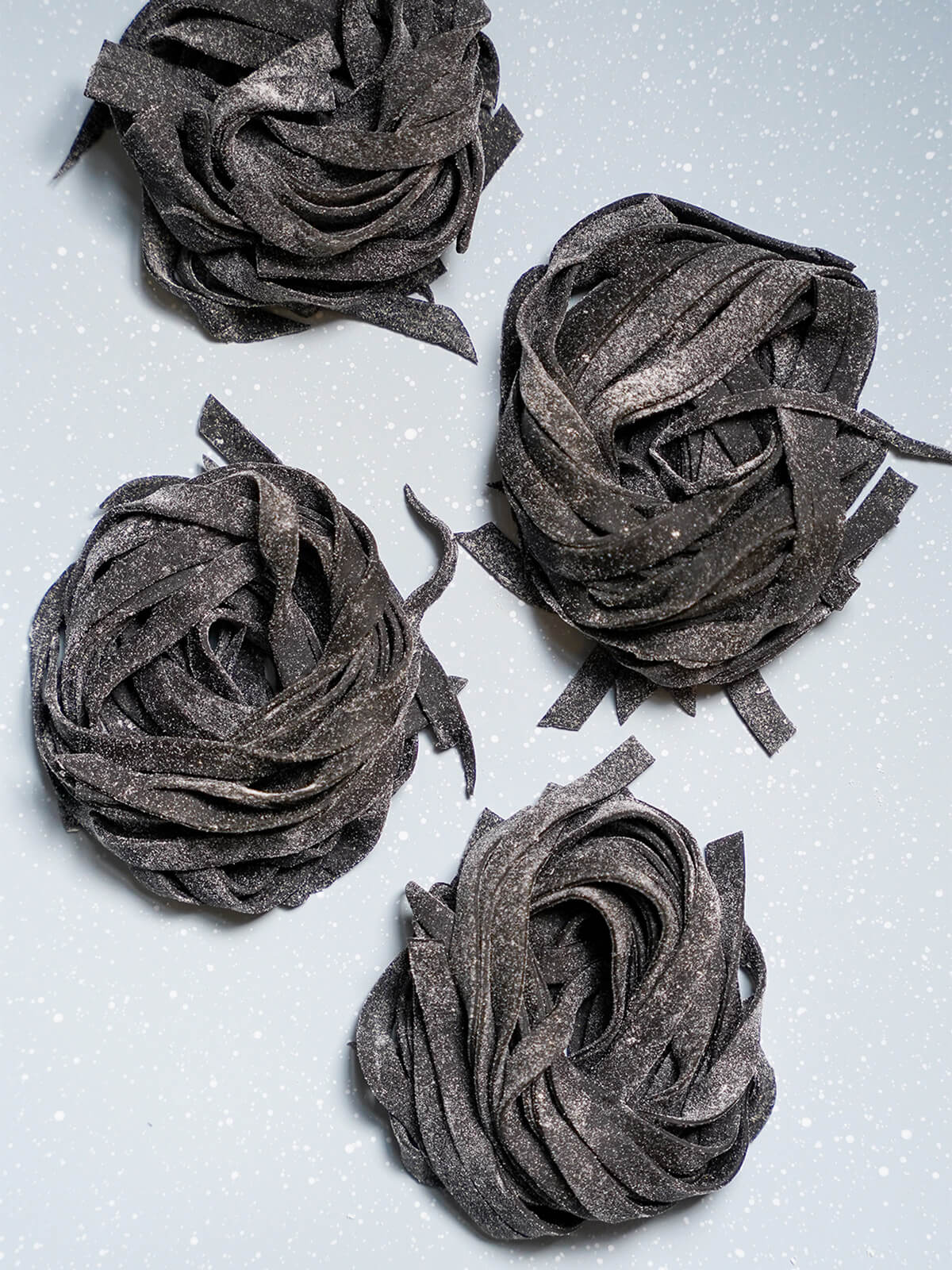overhead view of four stacks of squid ink pasta.