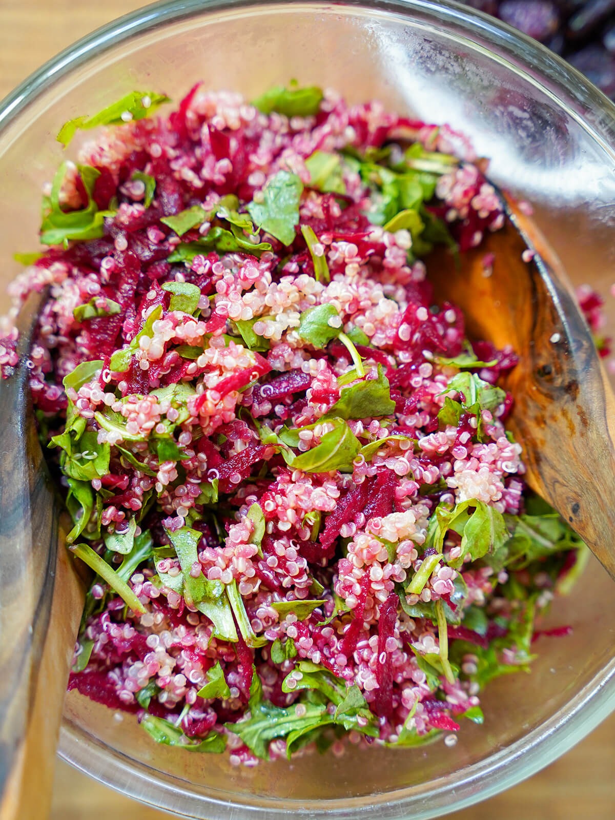 tossing together quinoa, beet and arugula in bowl.