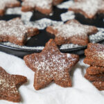 close up of a star shaped Basler brunsli, a Swiss chocolate almond cookie, with parts of others in background and to side.