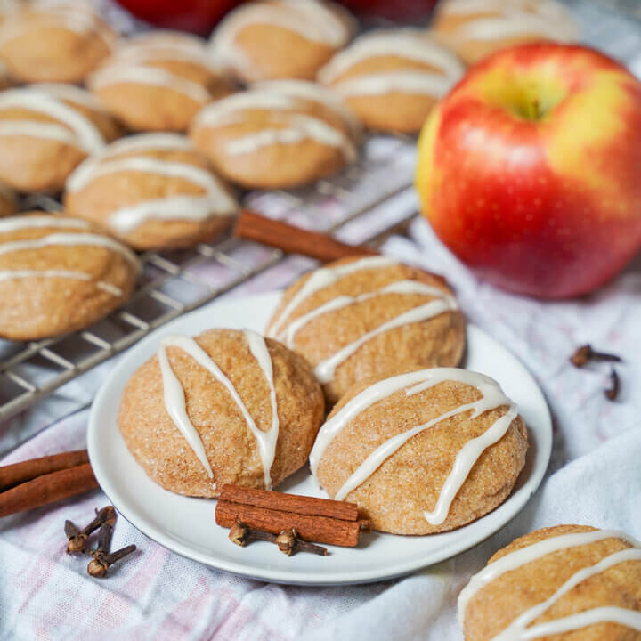 small plate of apple cider cookies with apple behind.