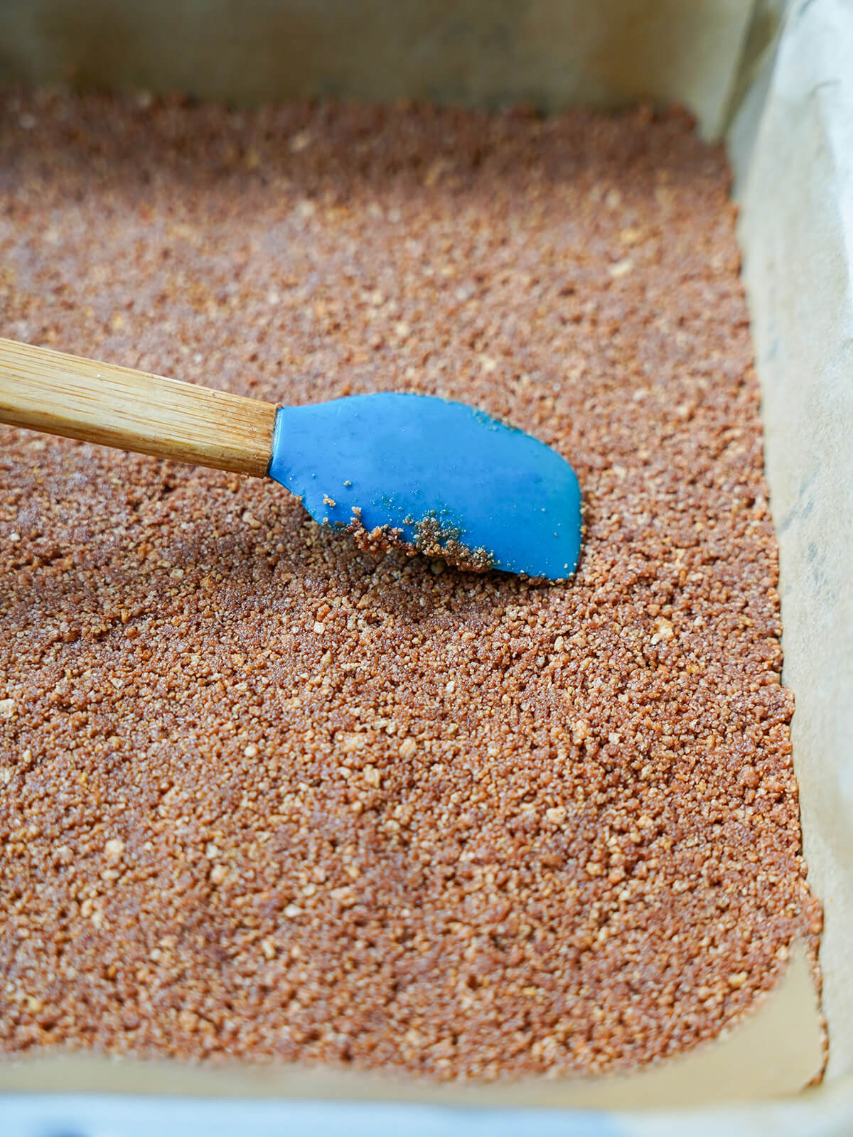 pressing cookie crumb layer for base into lined baking dish.