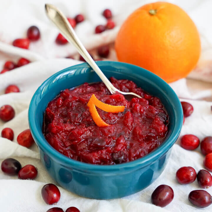 dish of cranberry sauce with orange with a whole orange behind dish.