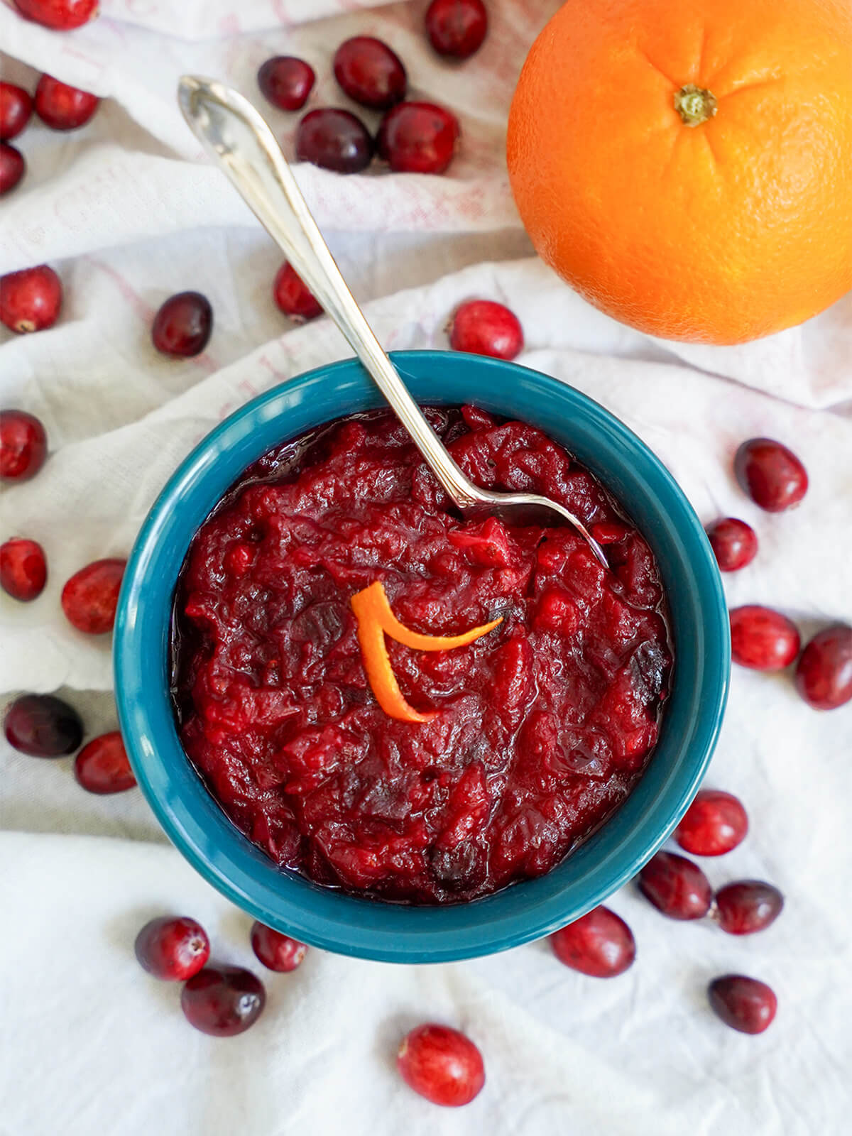 overhead view of a dish of cranberry sauce with orange with a spoon in it.