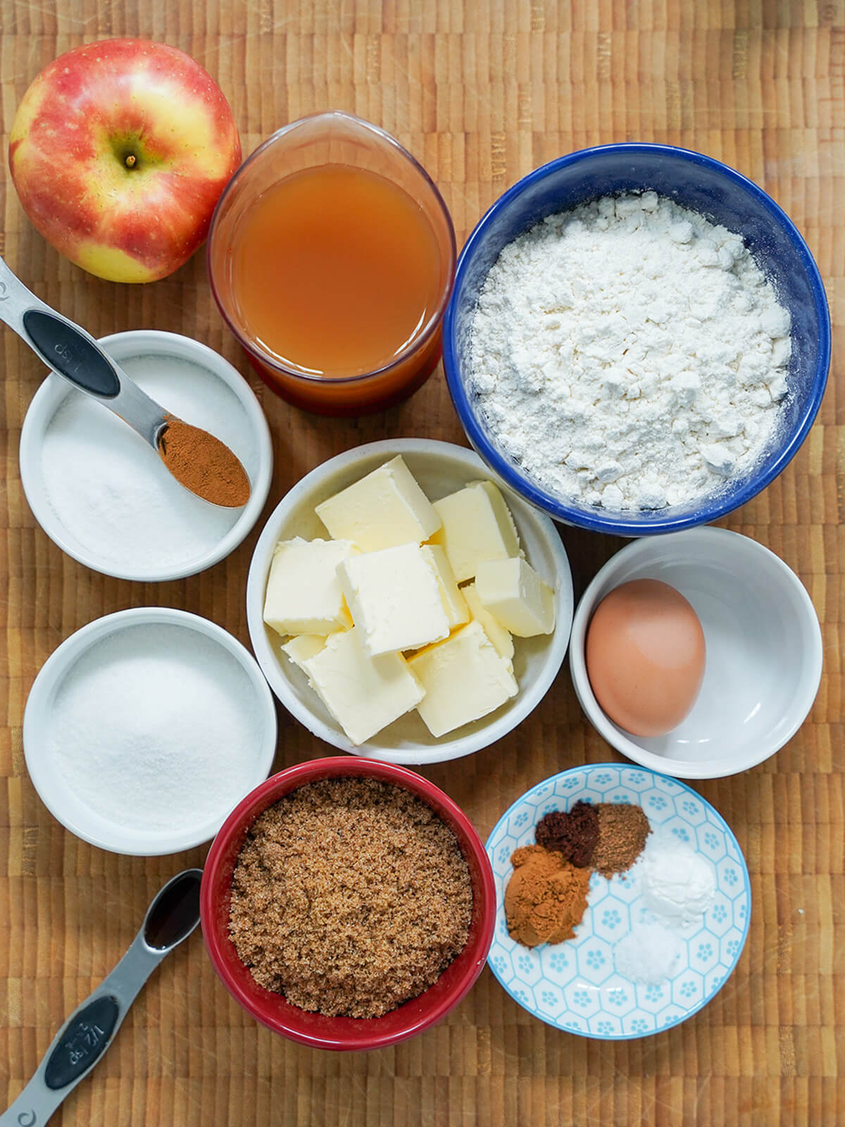 overhead view of bowls of flour, butter, sugars, spices, egg and measure of apple cider.