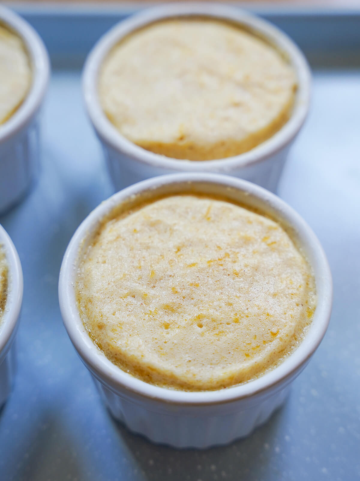 pumpkin souffle ready to bake souffle mixture in ramekins on a blue baking sheet before baking.