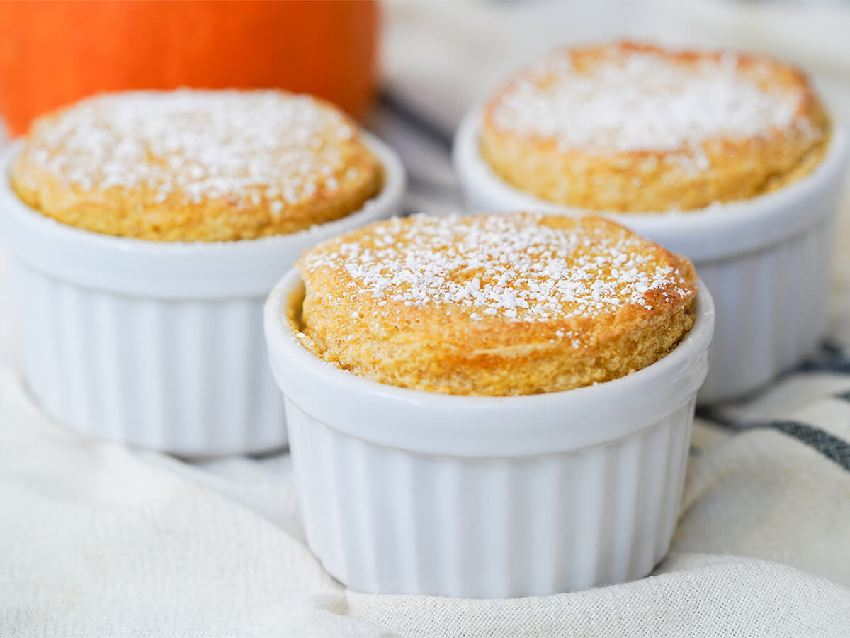 pumpkin souffle is a lovely fall-flavored dessert three pumpkin souffle dusted with sugar viewed from side.