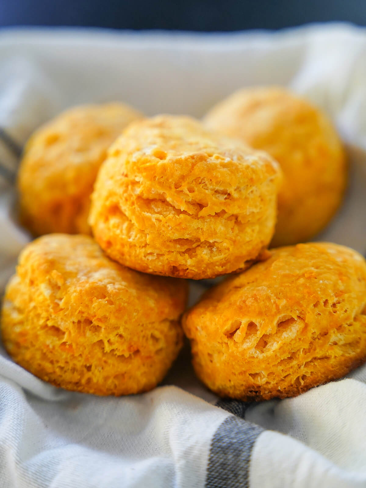 five sweet potato biscuits stacked in cloth lined basket.