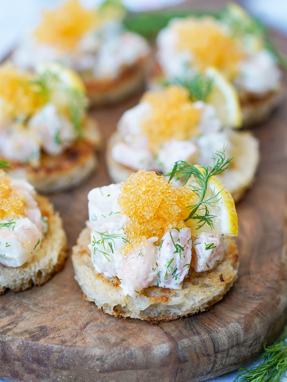 pieces of toast Skagen on a wooden board in two rows, focus on one at front.