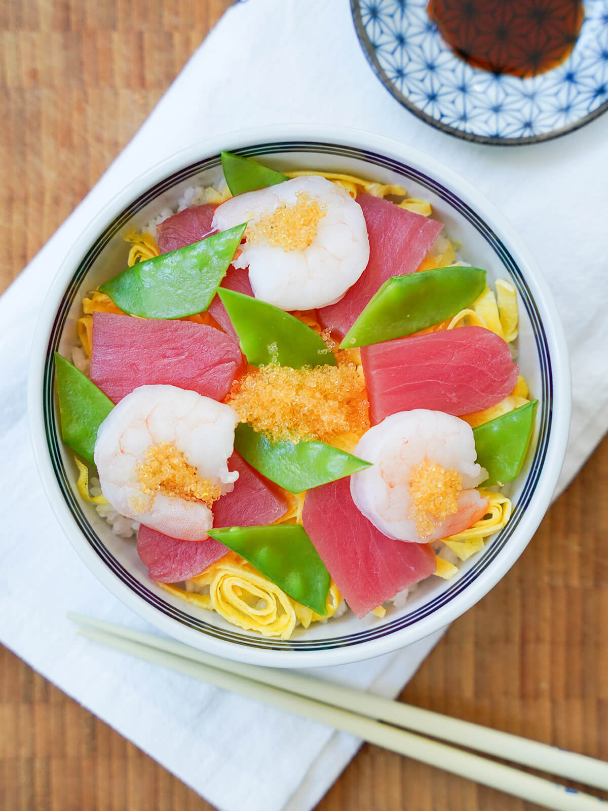 bowl of chirashi sushi from overhead with chopsticks sitting below bowl.