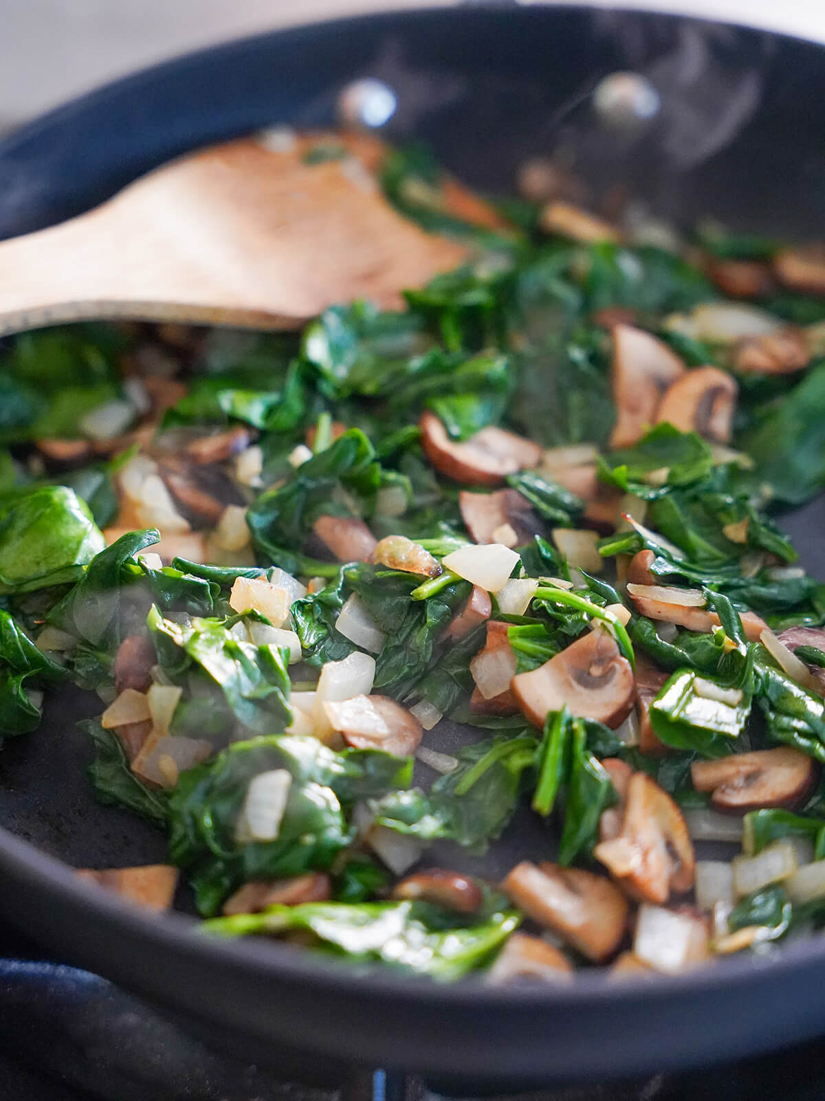 cooking spinach, mushrooms and onion in a skillet.