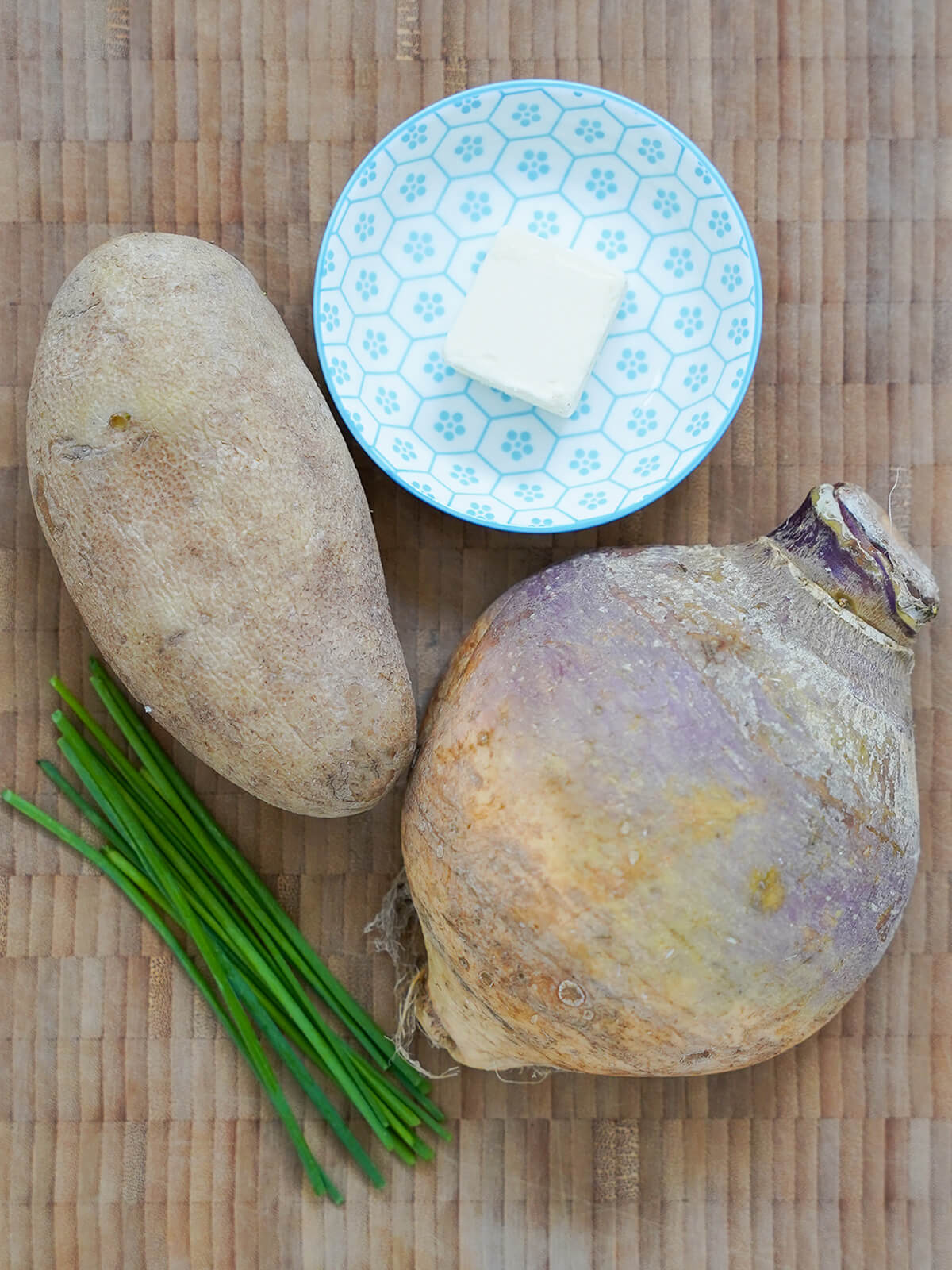 potato, rutabaga, dish with butter on it and stack of chives.