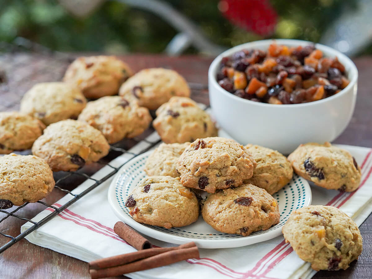 plate of mincemeat cookies with a bowl of mincemeat behind and more cookies on cooling rack to side.