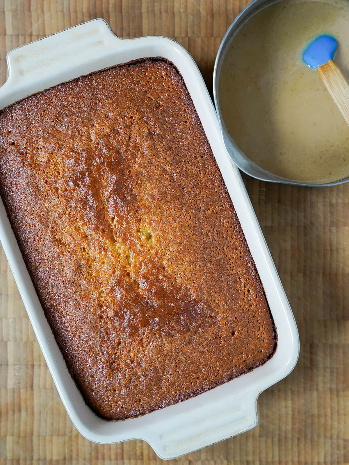 baked malva pudding with sauce in pan to side.