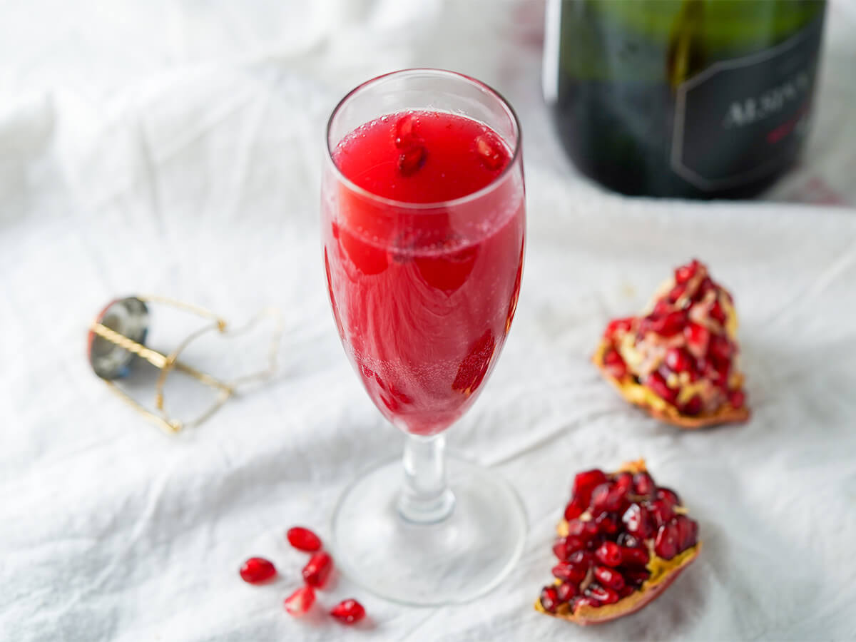 glass of pomegranate mimosa. glass of pomegranate mimosa garnished with pomegranate arils.