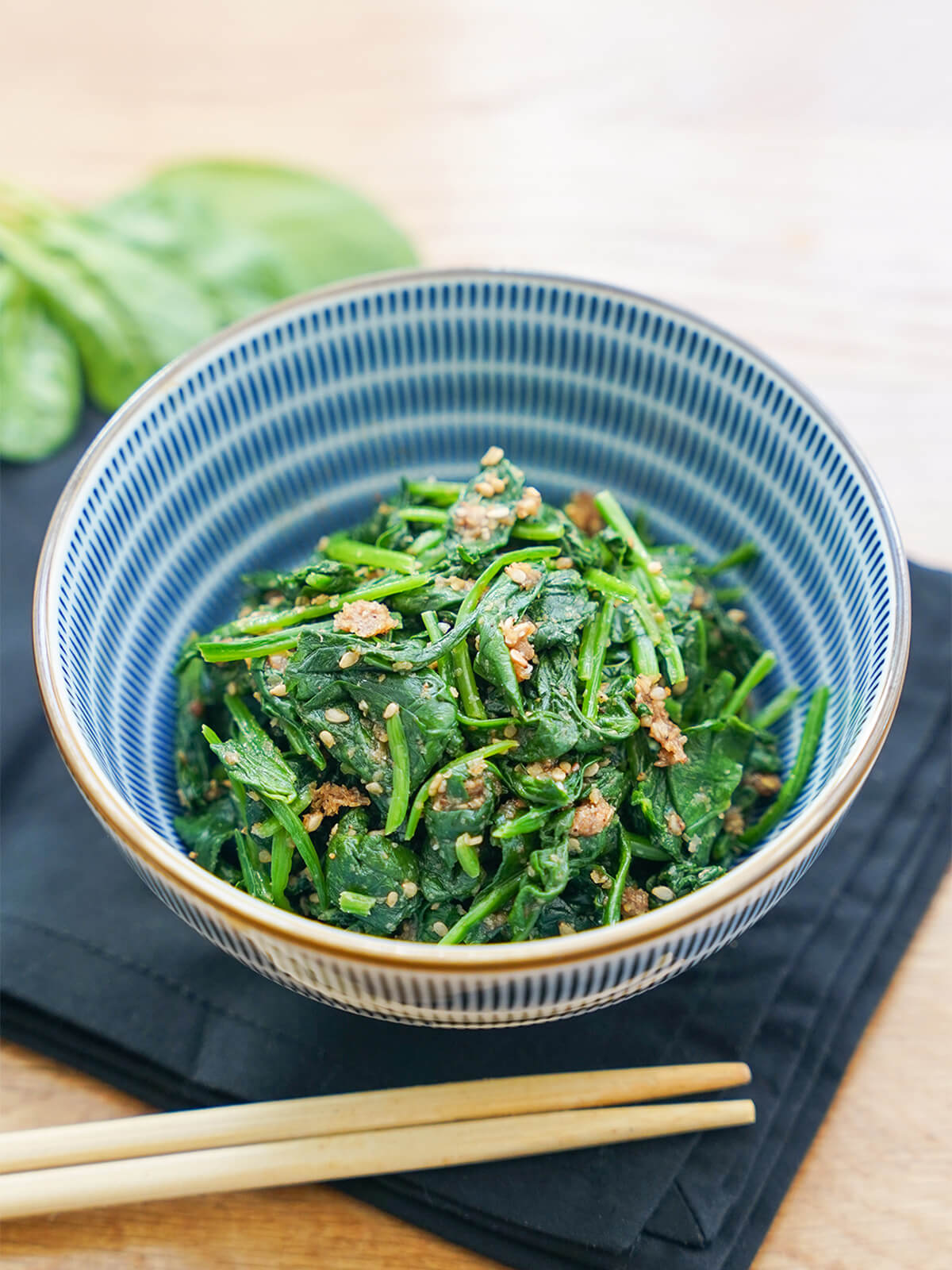 stack of Japanese spinach salad gomaae in bowl with chopsticks below.