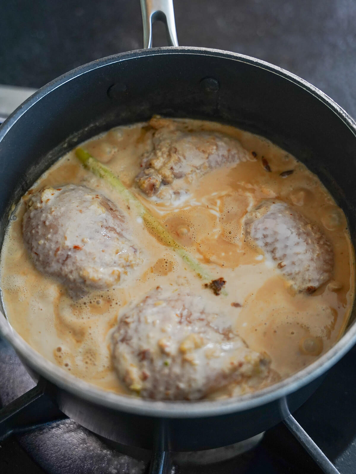 pieces of chicken in spiced coconut sauce before it starts simmer to reduce.