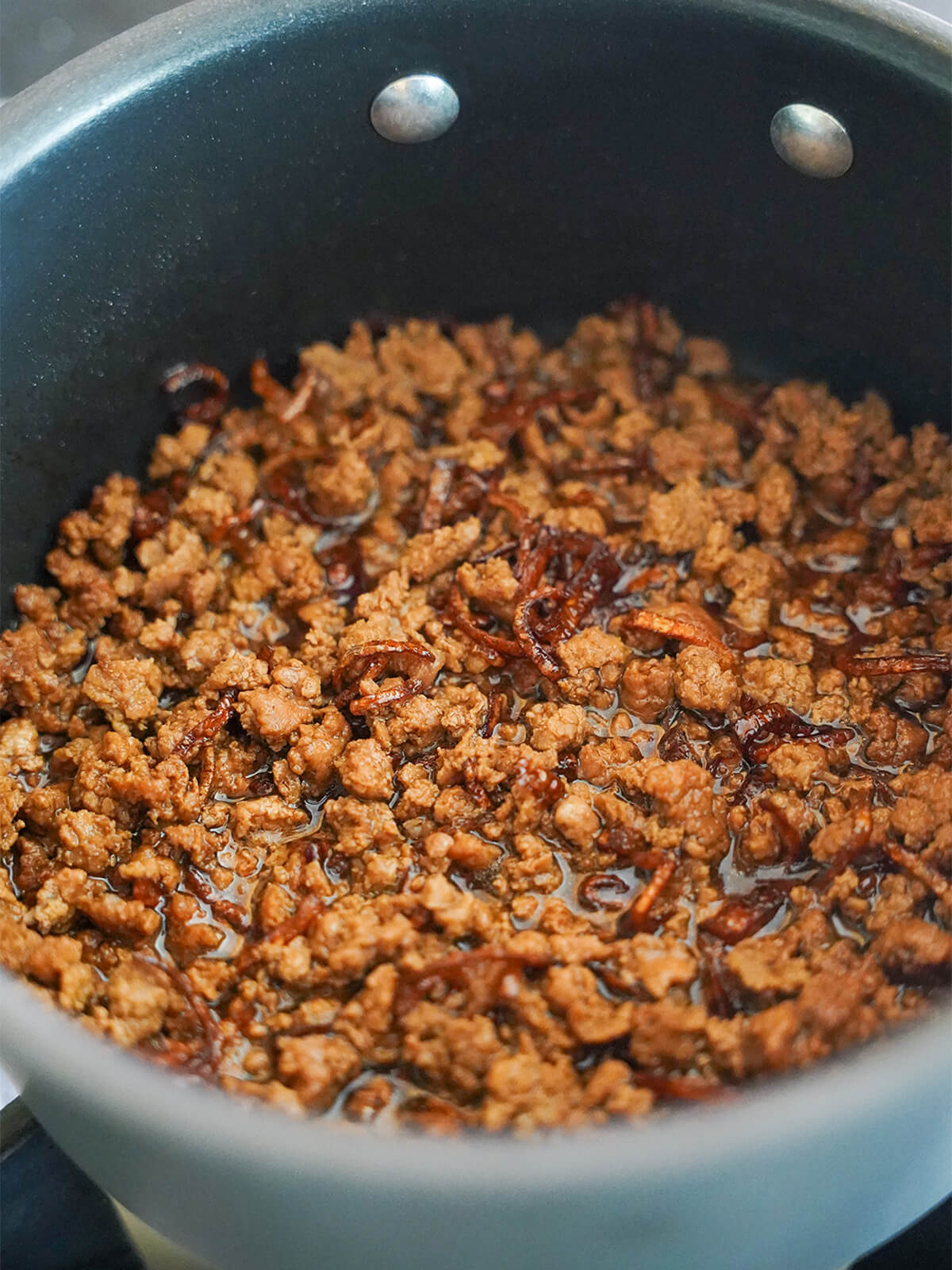 pork cooking in pot with soy mixture and fried shallots.