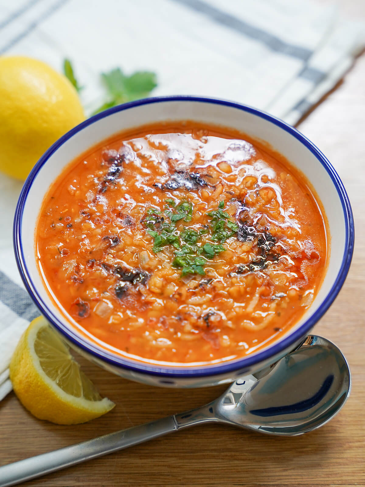 bowl of ezogelin soup, Turkish lentil bulgur soup with a slice of lemon and spoon below bowl.