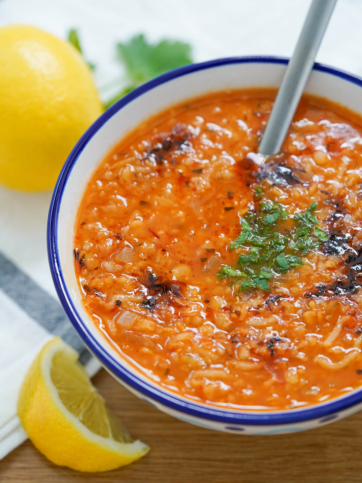 side view of bowl of ezogelin soup Turkish lentil bulgur soup with a spoon handle sticking out of the bowl.