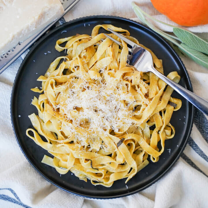 plate of fresh pumpkin pasta from overhead with fork in noodles and cheese on top.