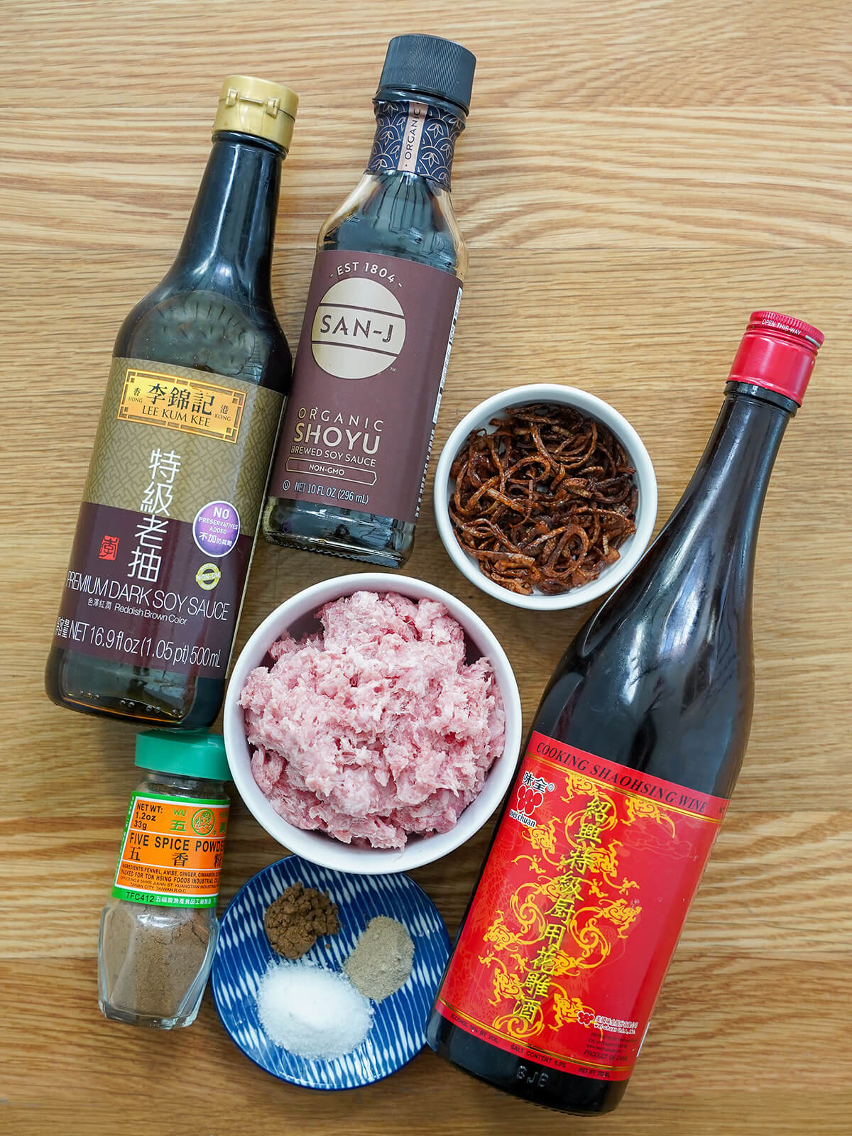 bottles of soy sauce, cooking with, bowls of ground pork and fried shallots and dish with spices.