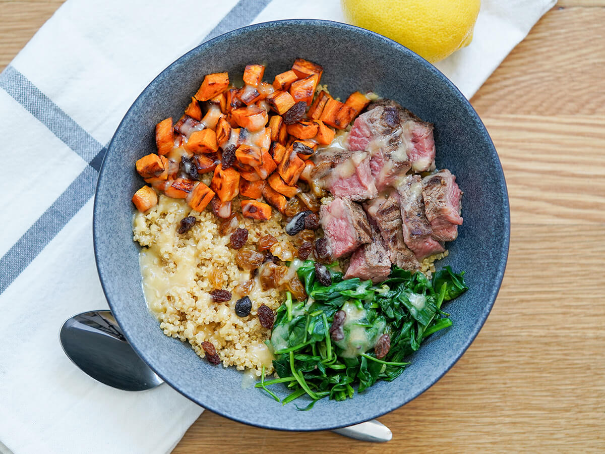 overhead view of leftover steak and quinoa bowl with spoon below bowl.