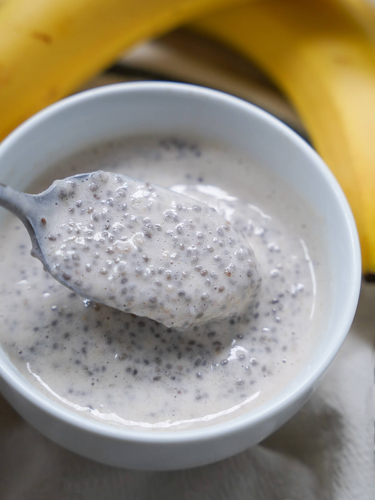 spoon showing gelled banana chia pudding in bowl.