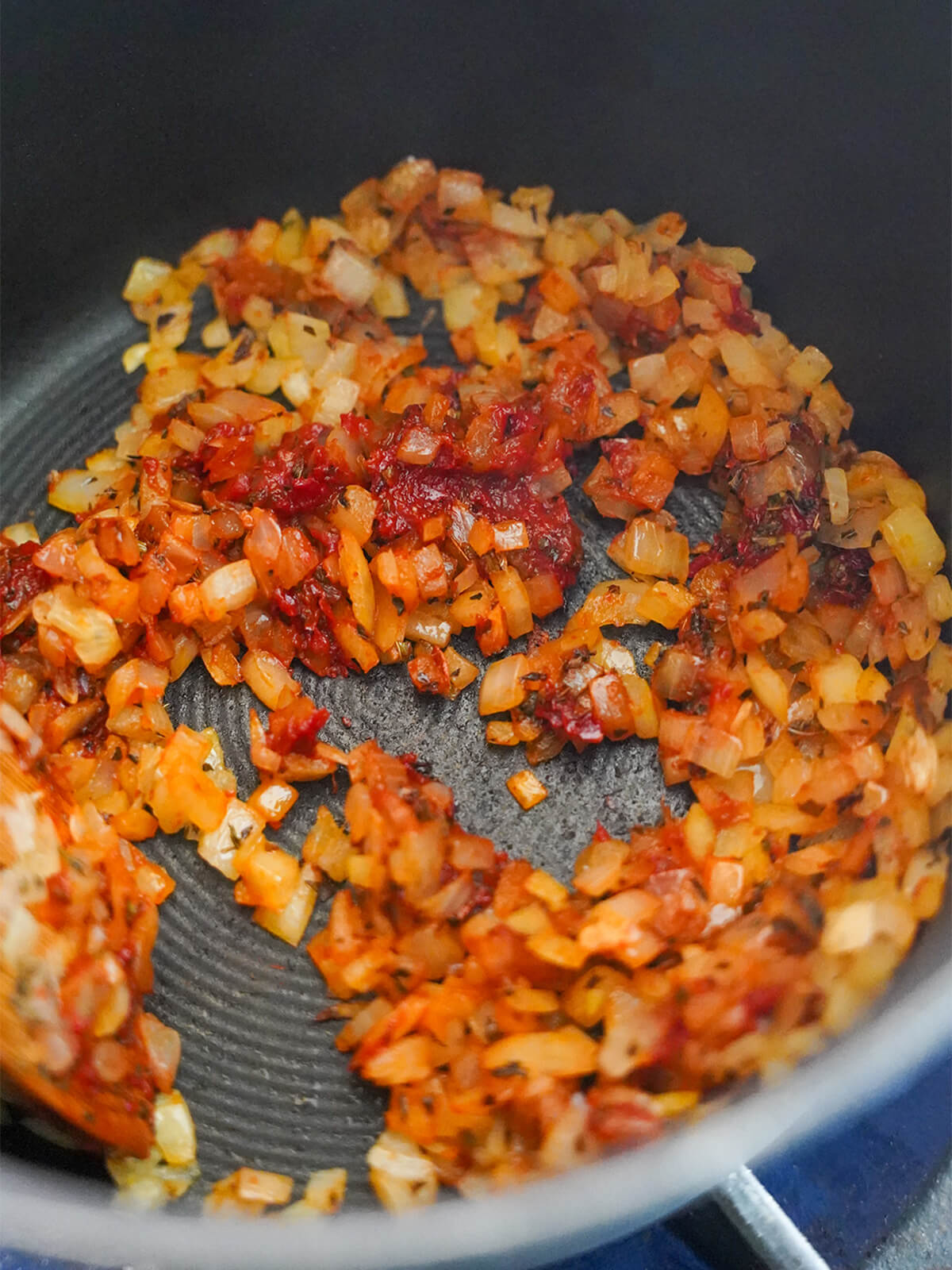 sauteed onions mixed with tomato and pepper paste at the bottom of a pot.