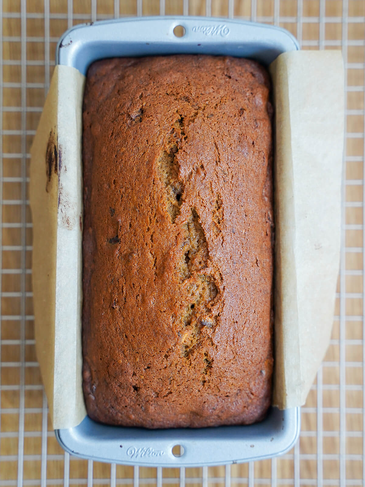 date and walnut loaf in loaf tin on cooling rack from overhead.