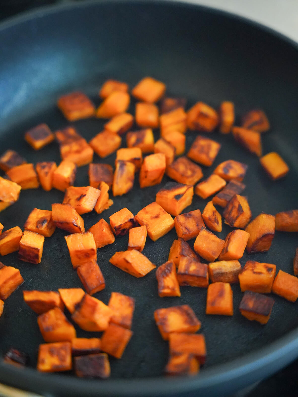 sauteeing cubes of sweet potato in a skillet.