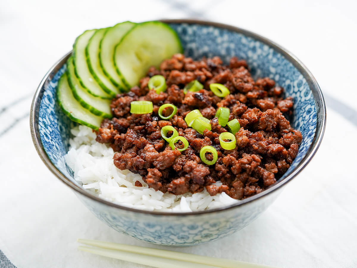 side view of bowl of Taiwanese minced pork rice garnished with green onion.