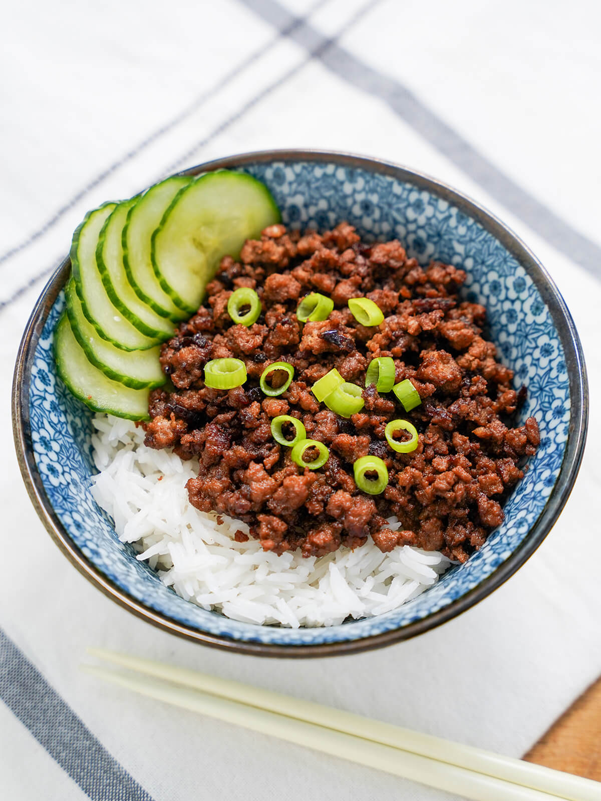 bowl of Taiwanese minced pork rice with cucumber to side of bowl and chopsticks below.