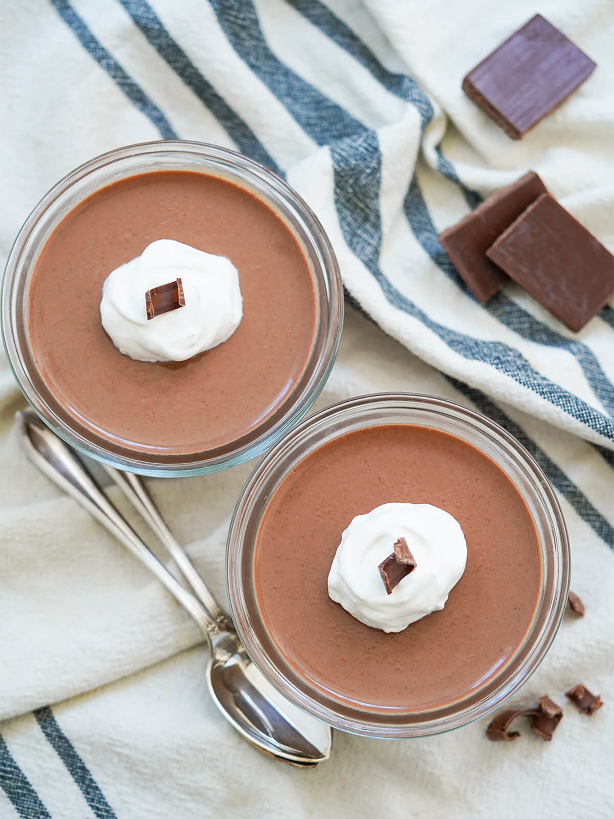 overhead view of two dishes of chocolate panna cotta topped with cream.