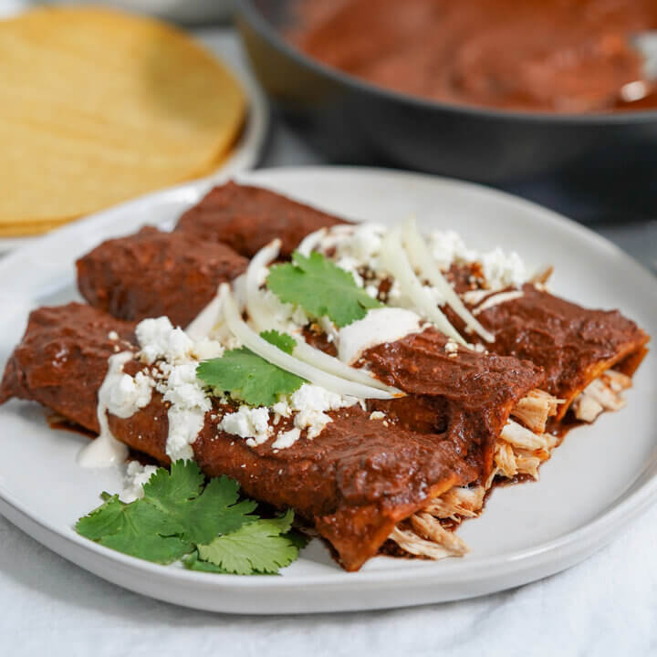 side view of three enmoladas on a plate.