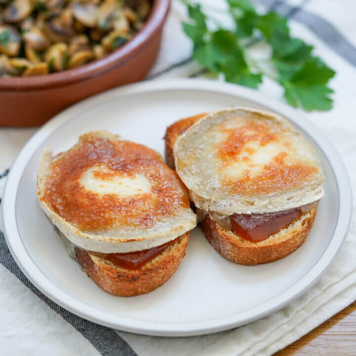 two slices of goat cheese toast with membrillo on small plate.