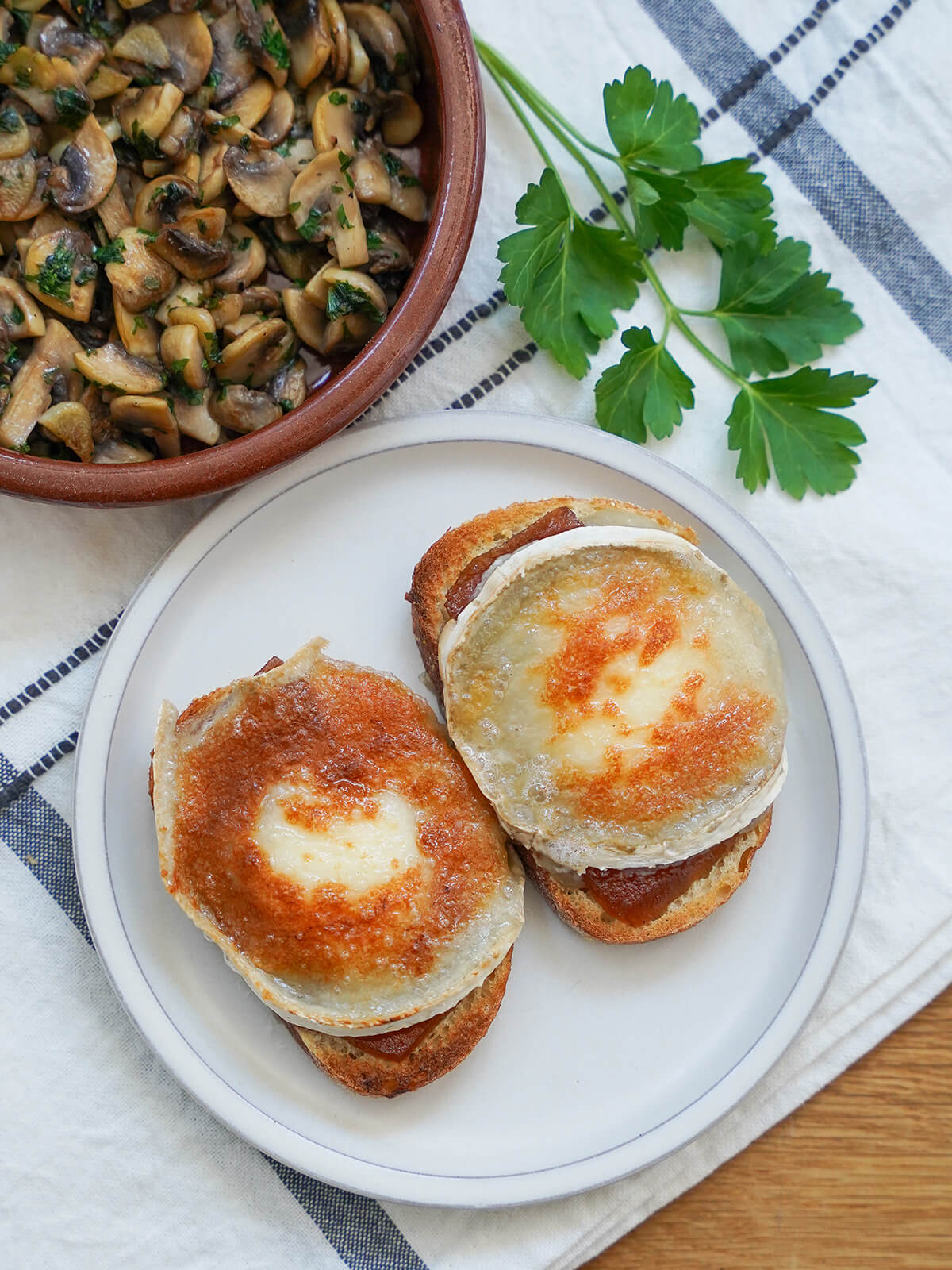 overhead view of slices of goat cheese toast with mushrooms in dish above.