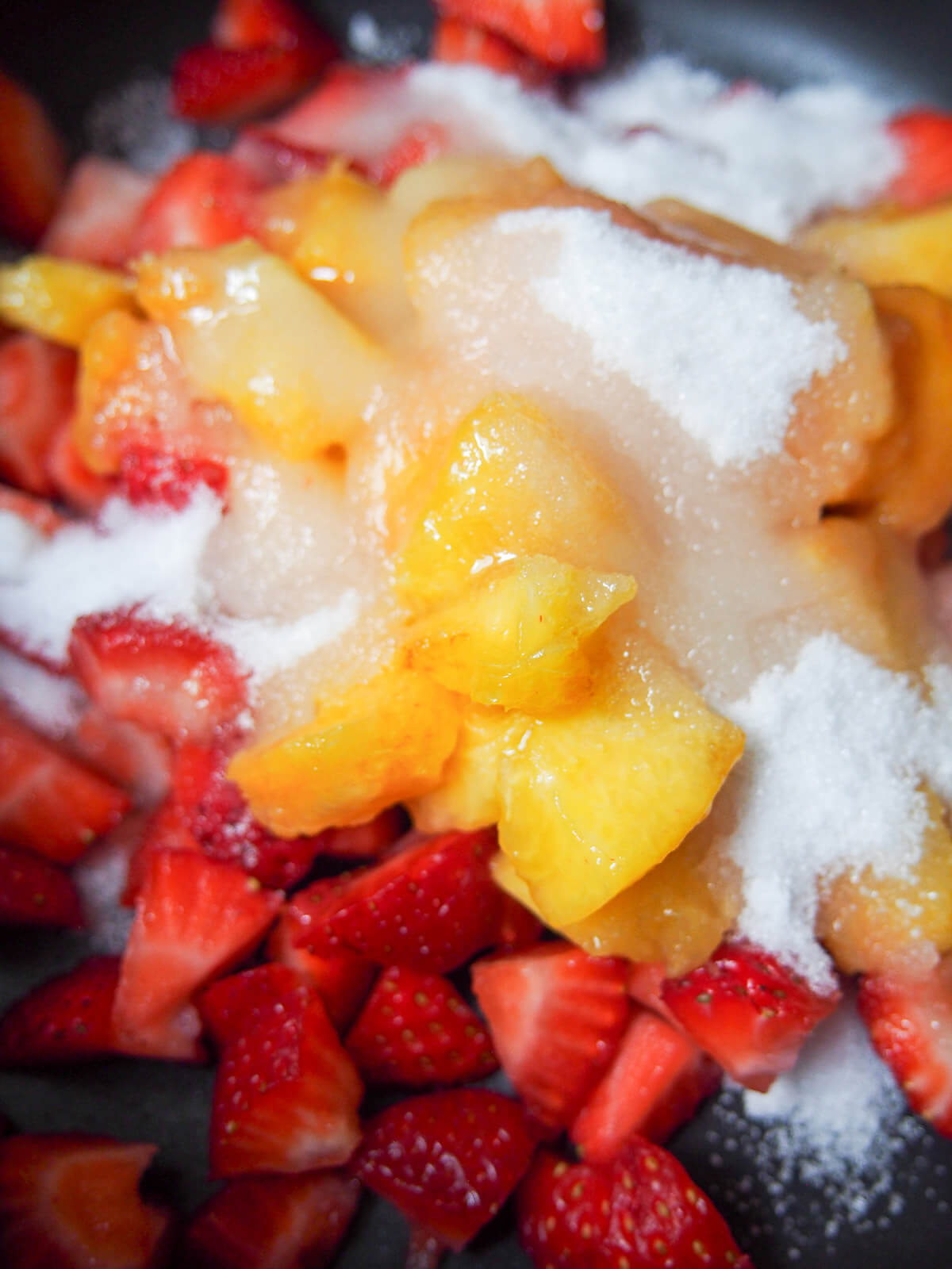 strawberry chunks, peach chunks with sugar over top in pot.