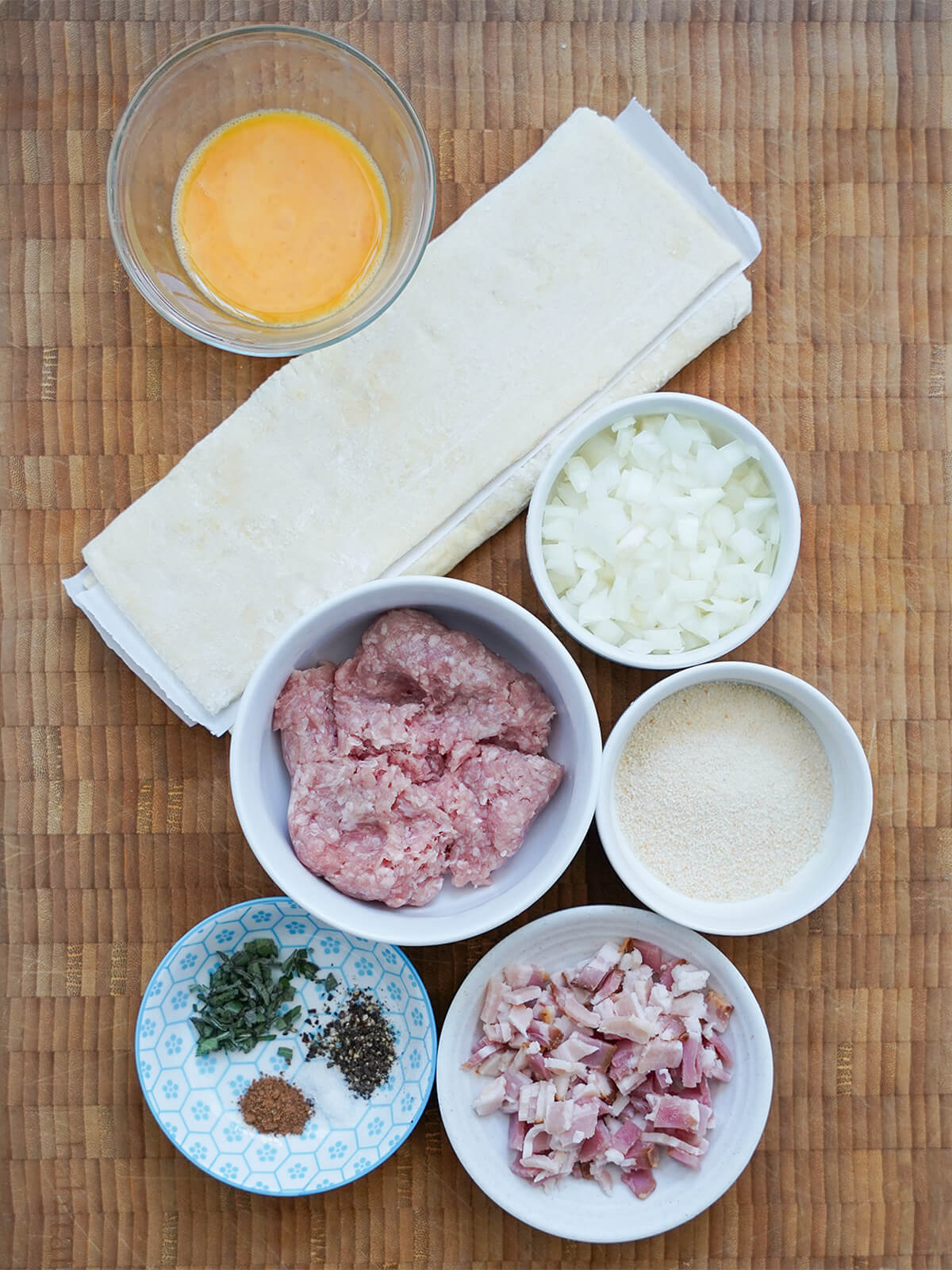 dishes of ground pork, bacon, breadcrumbs, onion, herbs and egg with folded puff pastry in between.