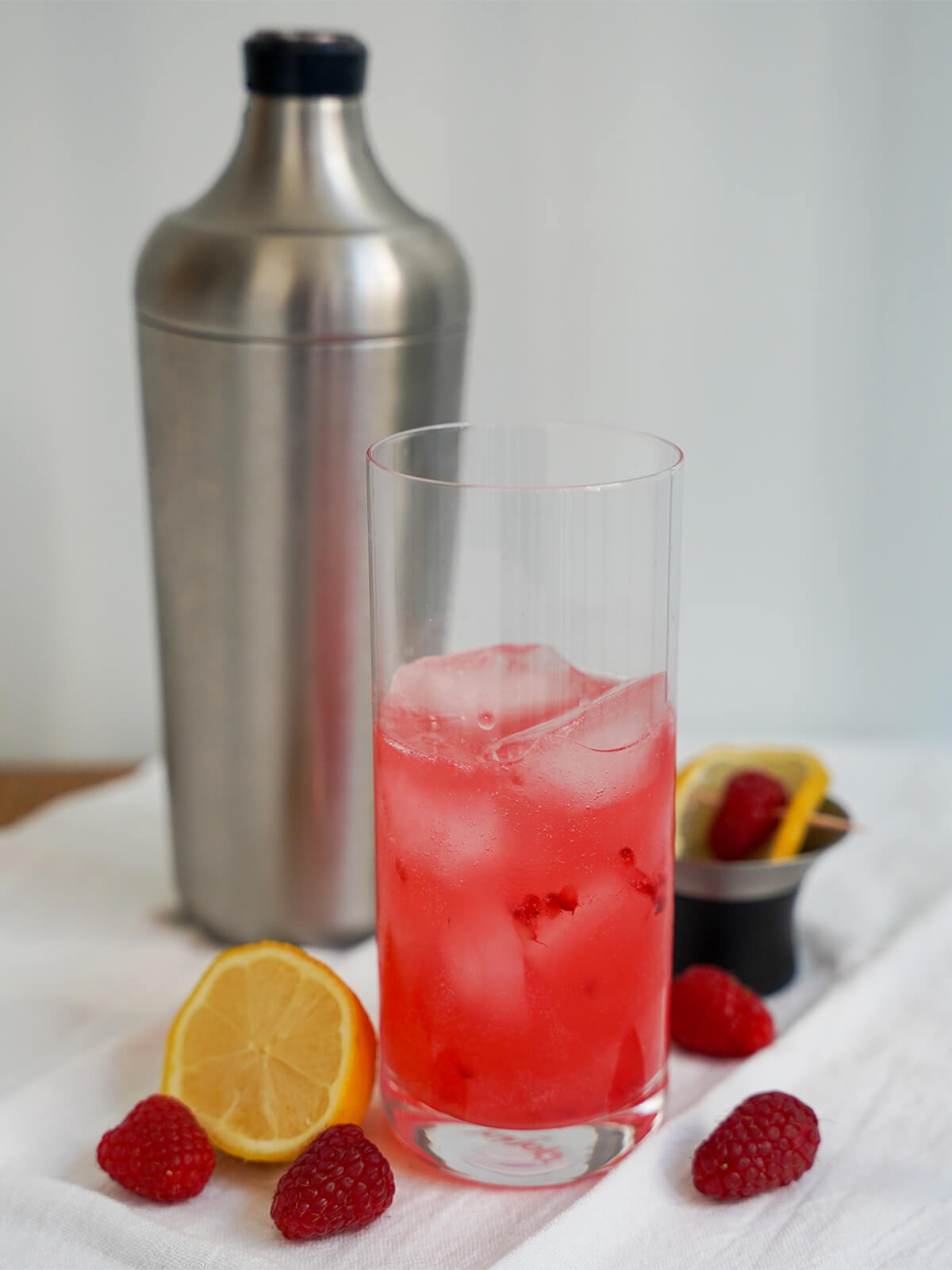 glass half full with raspberry, gin and lemon mixture over ice.