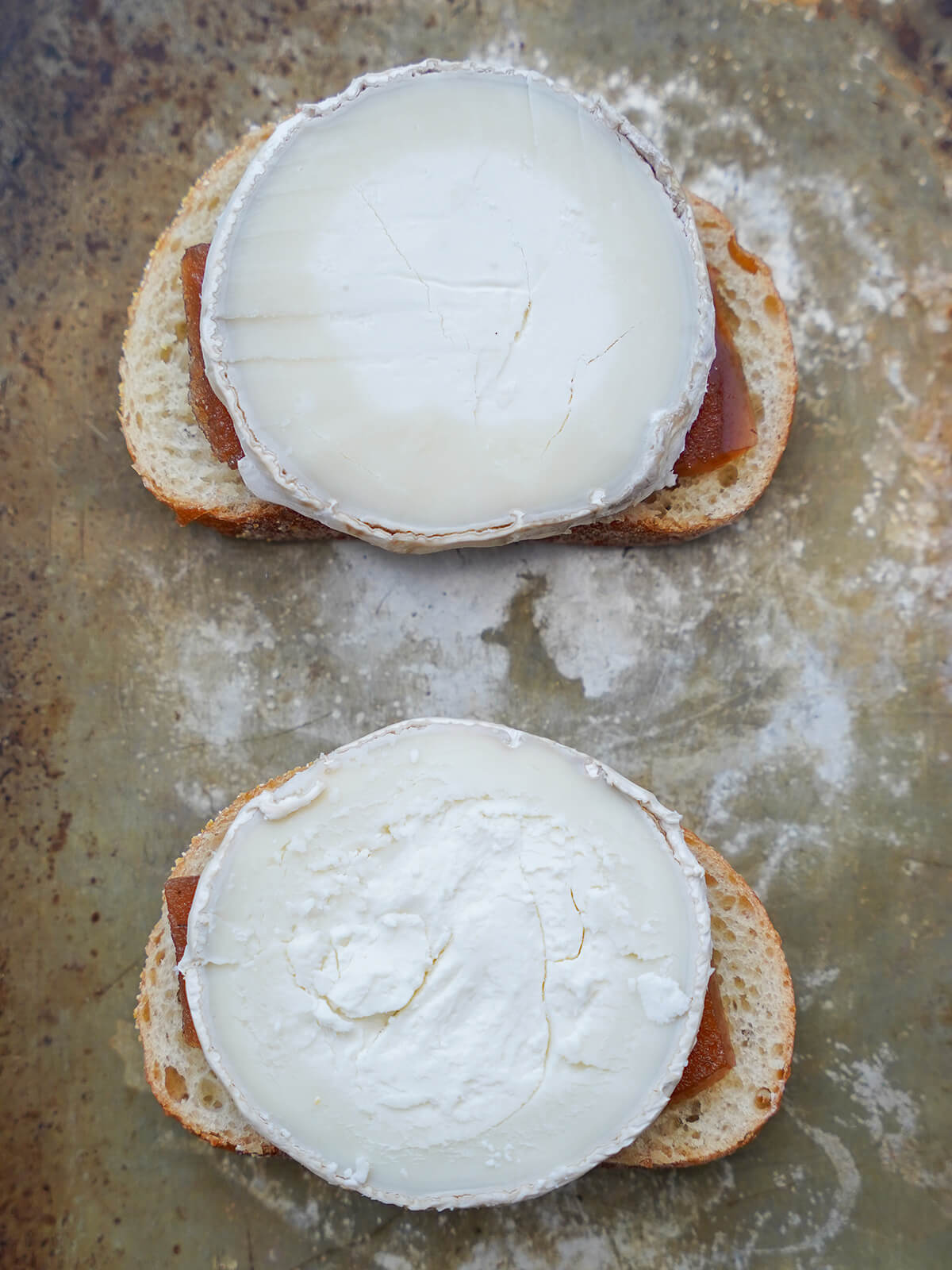 pieces of goat cheese sitting on top of slices of bread with membrillo sticking out a little in between.