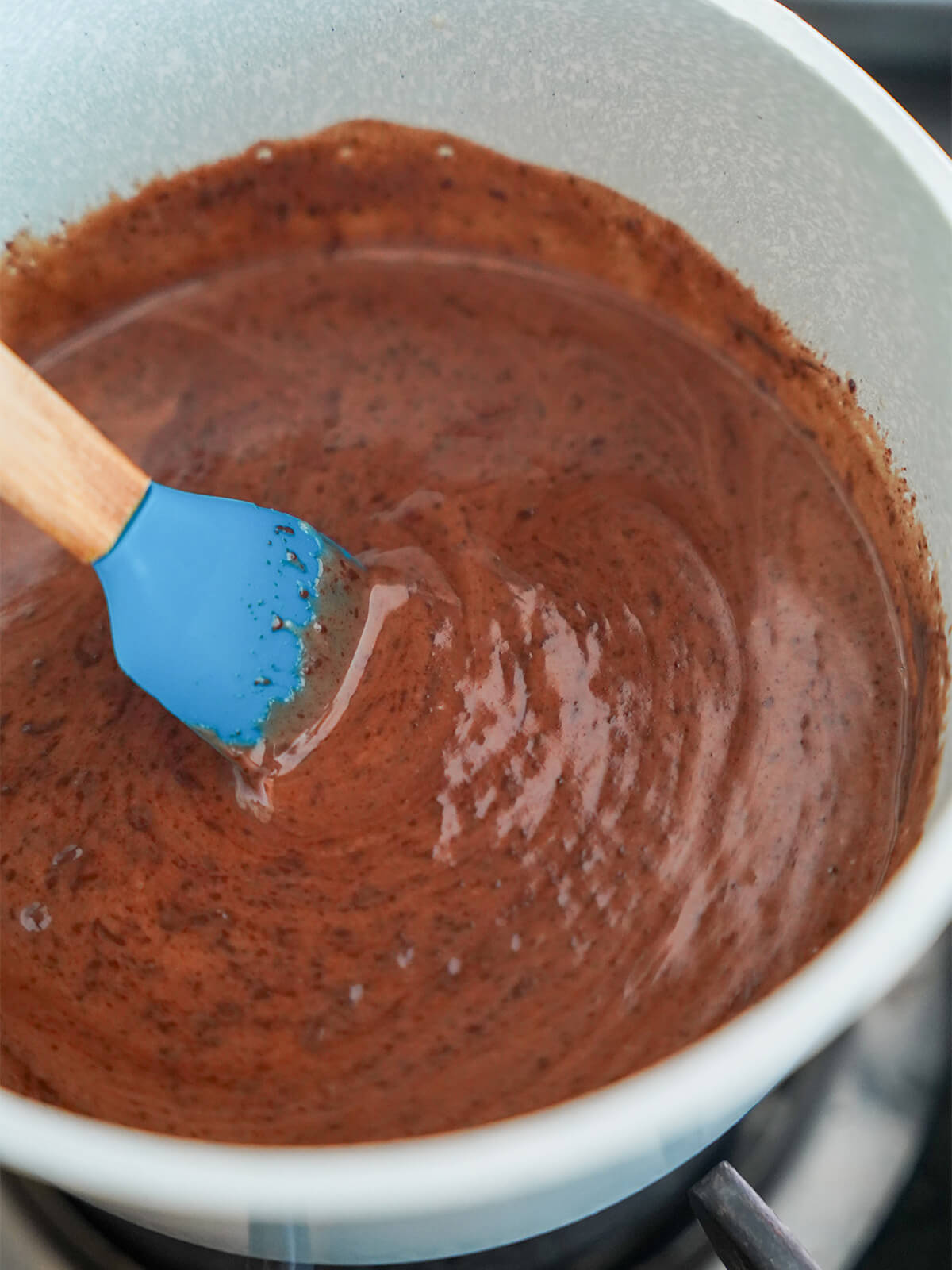 mixing chocolate into cream mixture in saucepan.