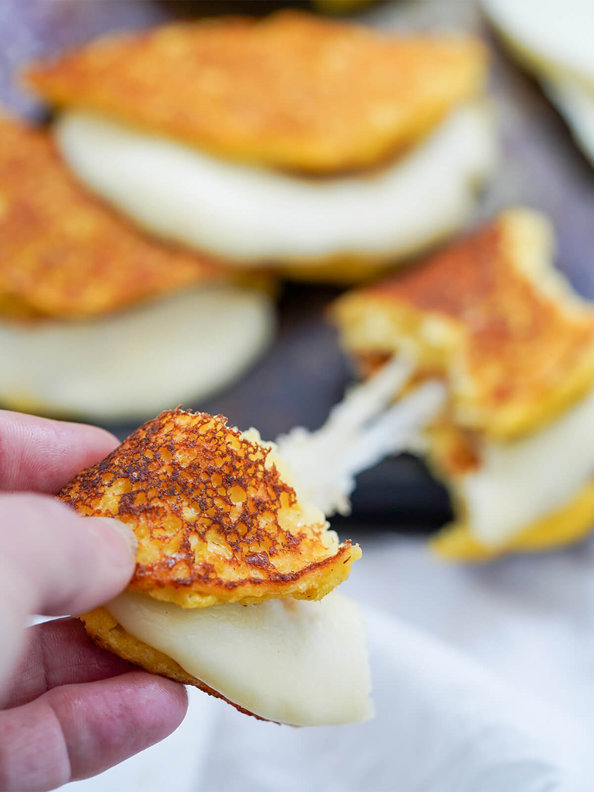 piece of a cachapa with cheese pull to other piece blurred below.