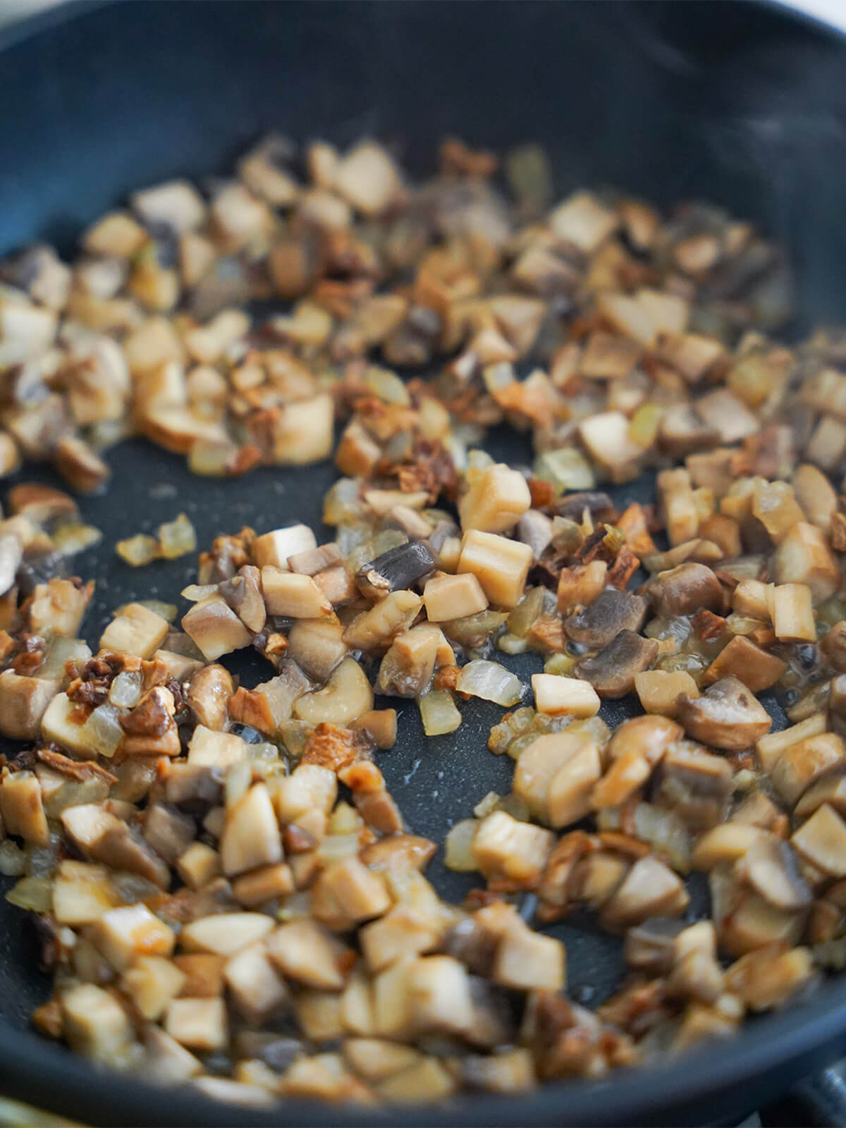 diced mushroom and porcini cooking in skillet with fine diced onion.