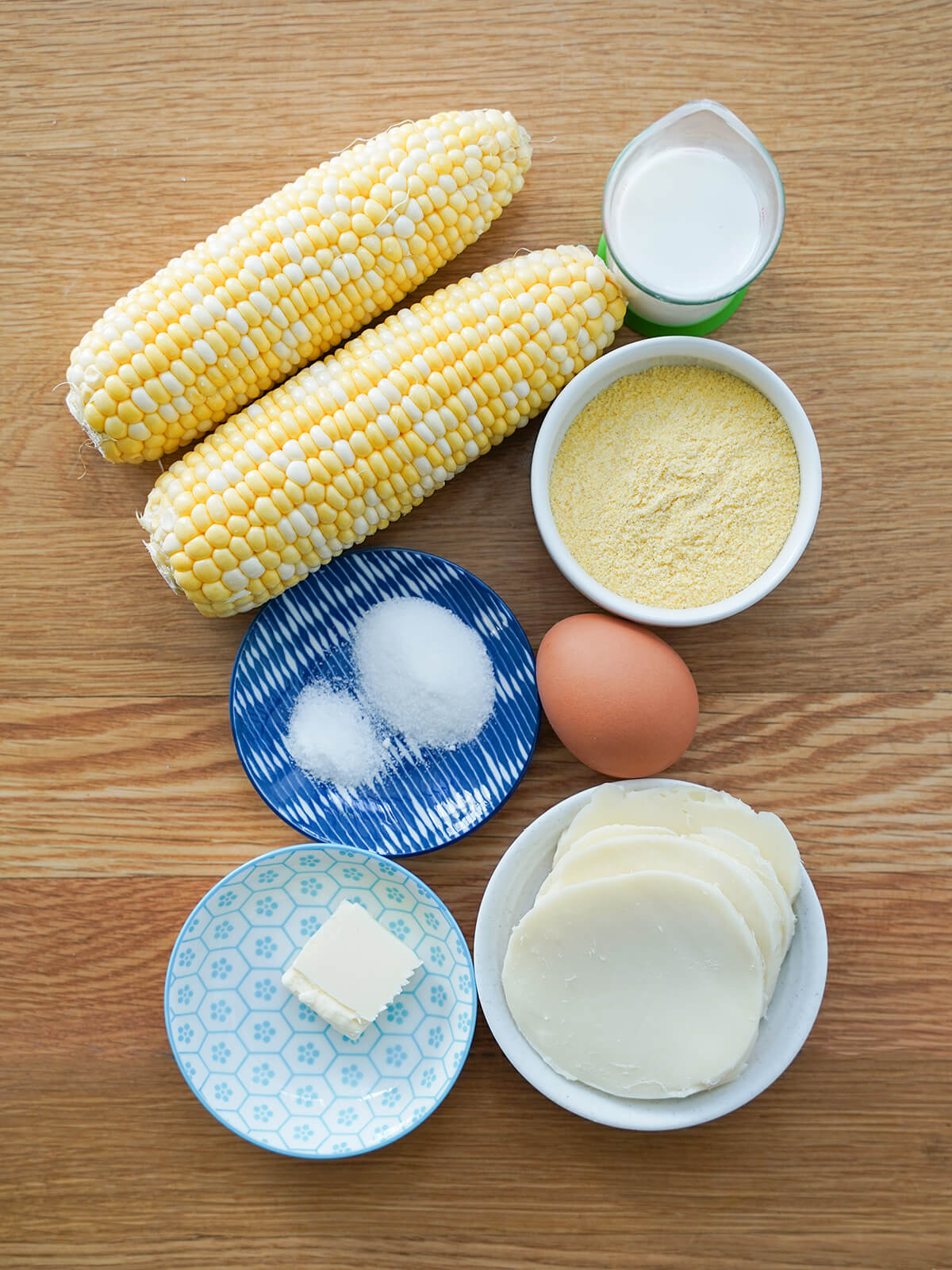 ears of corn, egg and dishes with corn meal, milk, cheese slices, butter and baking powder.