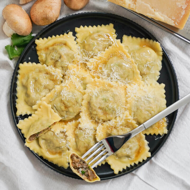 plate of mushroom ravioli with fork resting on top.
