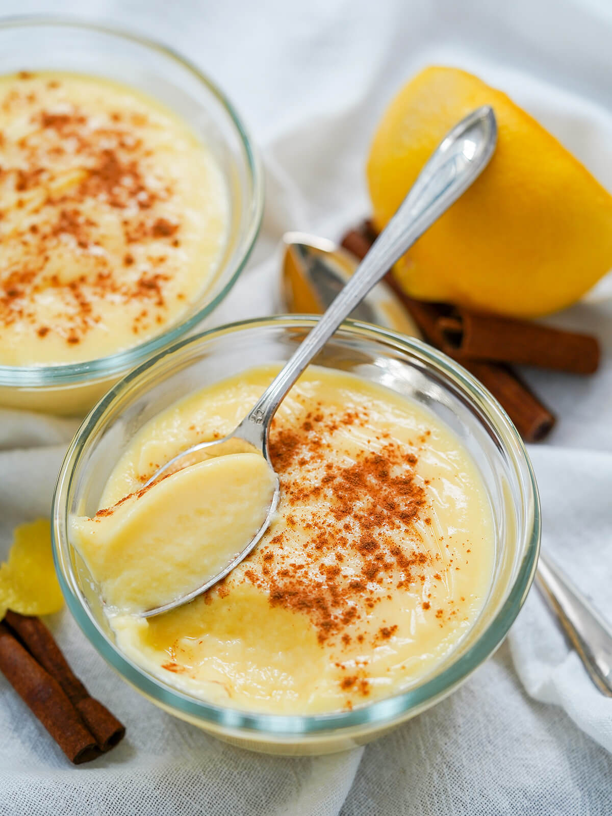 a dish of natillas, Spanish custard with spoon resting on top with some custard in it.