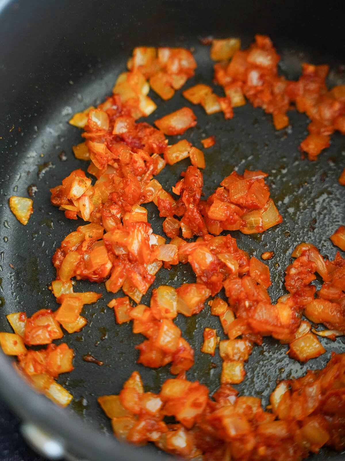 softened onion colored orange from tomato and chili paste in pot.